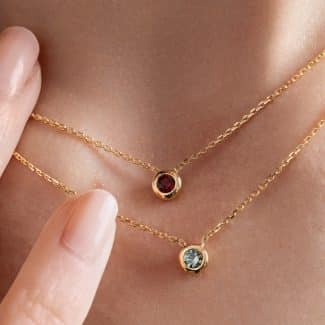 Collier grenat et collier saphir teal portés - or jaune - modèle Serti clos de Charles Arteon Joaillerie