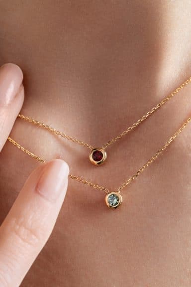 Collier grenat et collier saphir teal portés - or jaune - modèle Serti clos de Charles Arteon Joaillerie